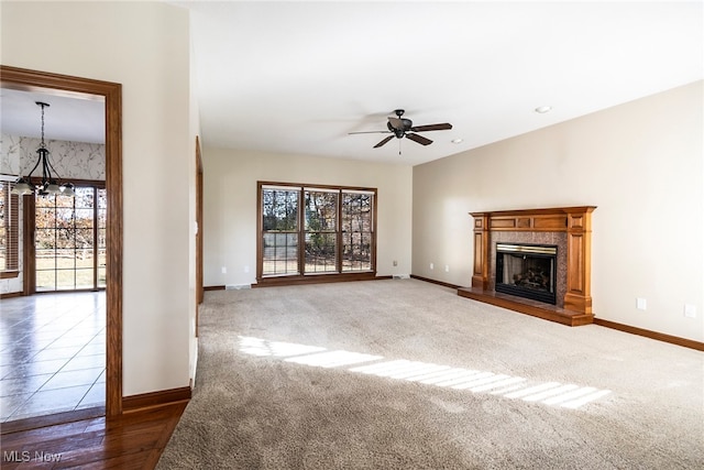 unfurnished living room featuring ceiling fan with notable chandelier, dark hardwood / wood-style flooring, and a wealth of natural light