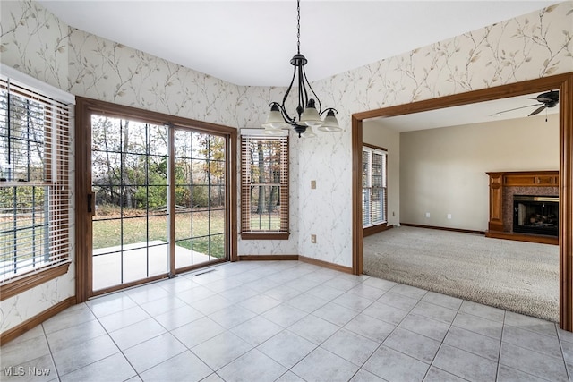 unfurnished dining area with light colored carpet and ceiling fan with notable chandelier