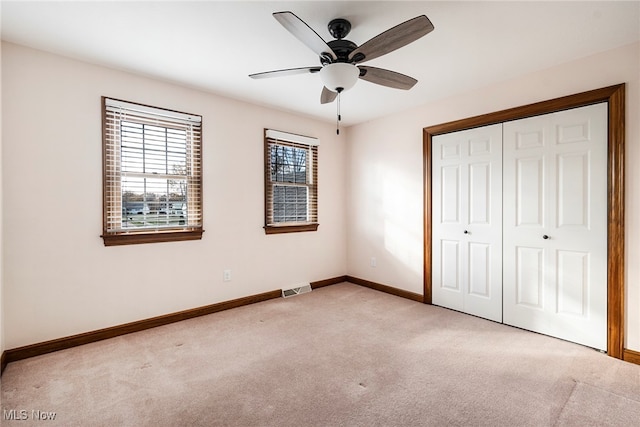 unfurnished bedroom with a closet, light colored carpet, and ceiling fan