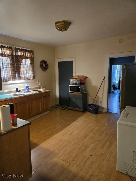 kitchen featuring appliances with stainless steel finishes, sink, washer / clothes dryer, and light hardwood / wood-style flooring