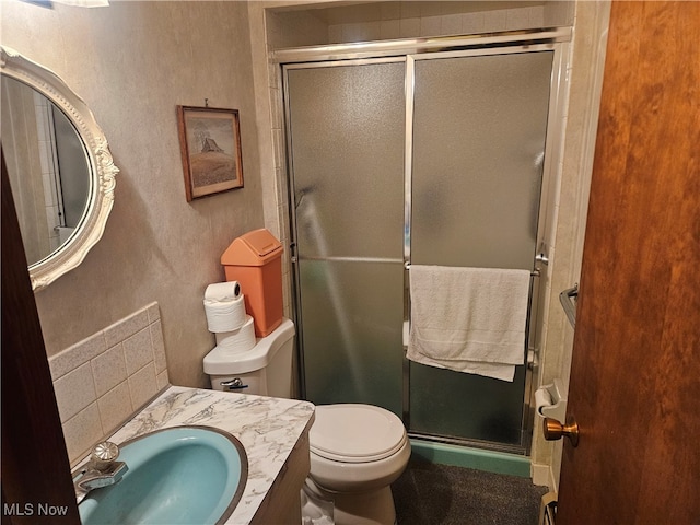 bathroom featuring a shower with door, vanity, and toilet