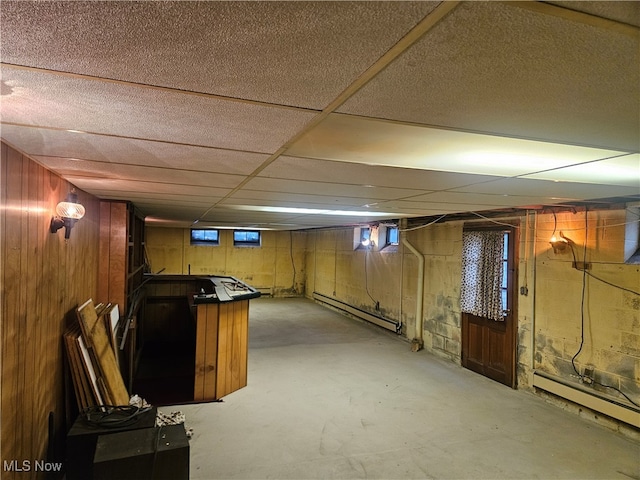 basement with wooden walls and a baseboard radiator