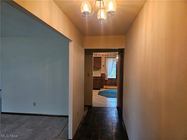 hall with an inviting chandelier, a textured ceiling, and a baseboard radiator