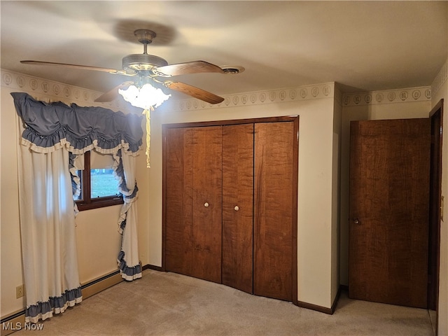 unfurnished bedroom featuring light carpet, a closet, ceiling fan, and a baseboard heating unit