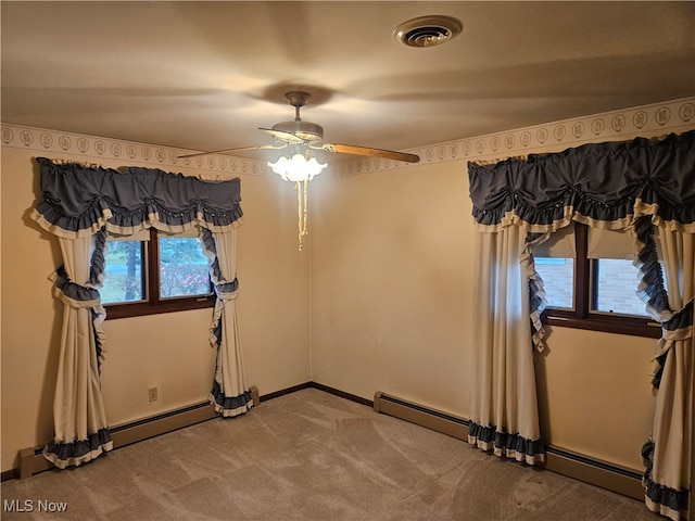 empty room with carpet flooring, baseboard heating, and a wealth of natural light