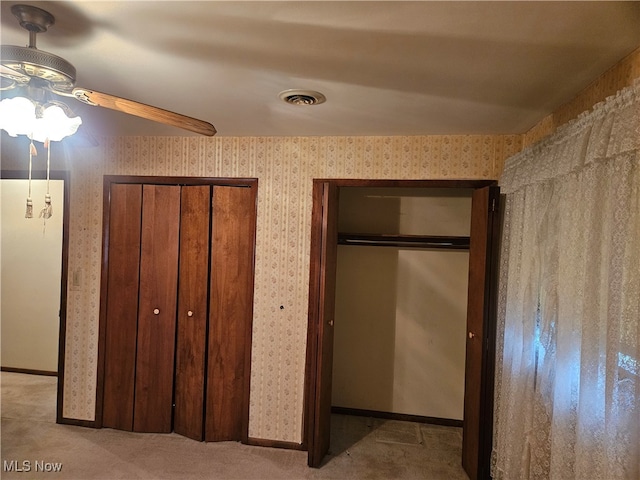 unfurnished bedroom with ceiling fan, light carpet, and multiple closets