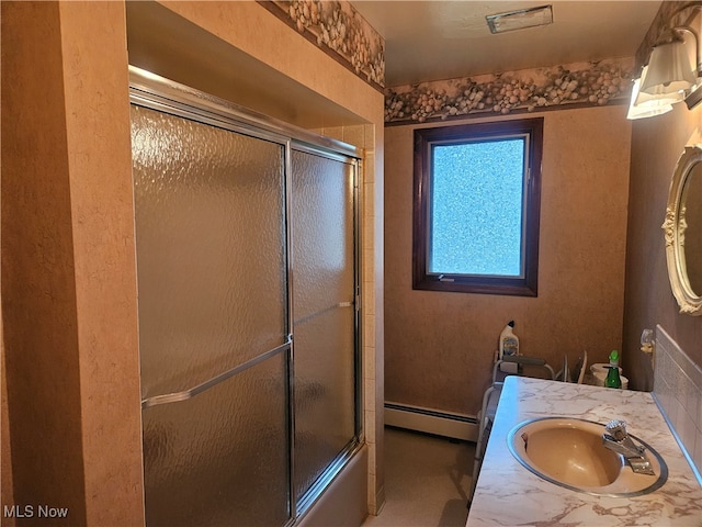 bathroom with vanity, combined bath / shower with glass door, and baseboard heating