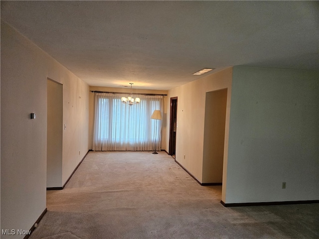 carpeted empty room with a chandelier and a textured ceiling