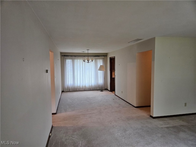 carpeted empty room with a chandelier