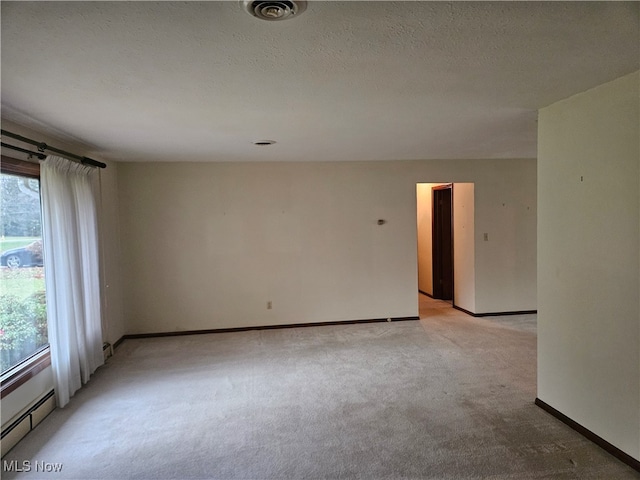 carpeted empty room with a textured ceiling and a baseboard heating unit