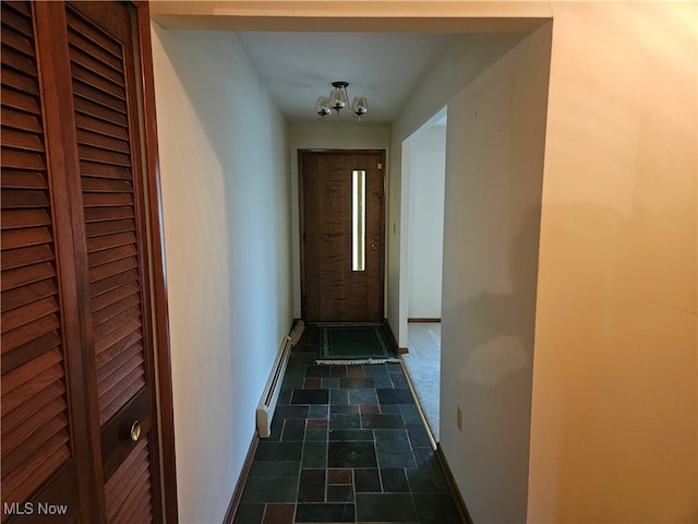 corridor featuring a baseboard heating unit and a notable chandelier