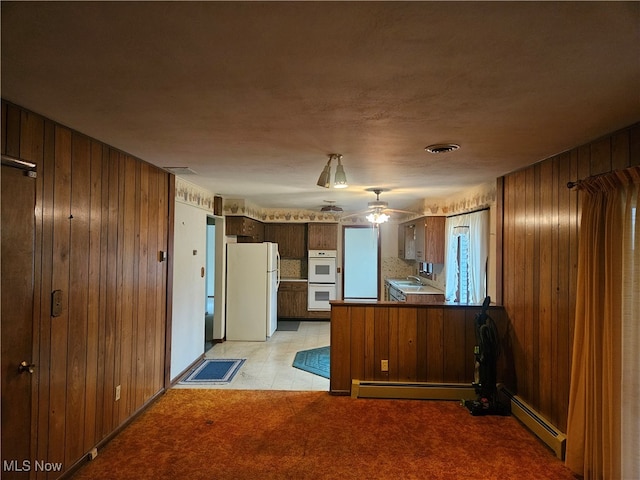 kitchen with wood walls, white appliances, light carpet, baseboard heating, and kitchen peninsula