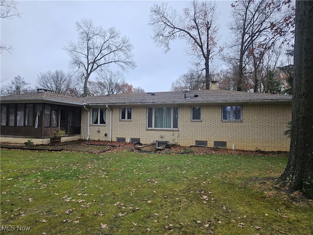 rear view of property with a sunroom and a lawn