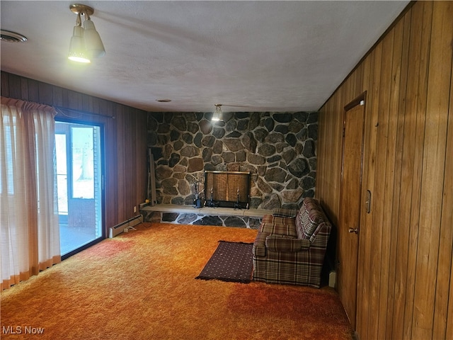 unfurnished room featuring baseboard heating, wood walls, a fireplace, and carpet