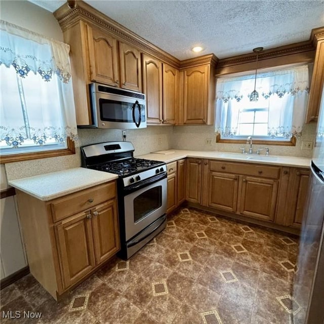 kitchen featuring appliances with stainless steel finishes, a textured ceiling, decorative light fixtures, and sink