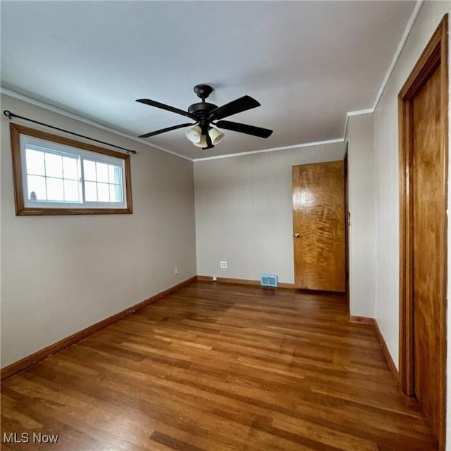 empty room with ceiling fan, wood-type flooring, and ornamental molding