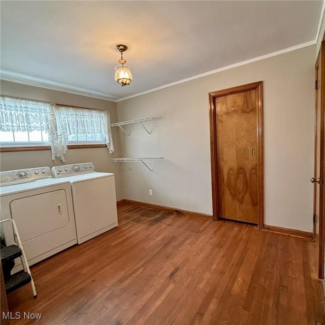 laundry area featuring washing machine and dryer, wood-type flooring, and crown molding