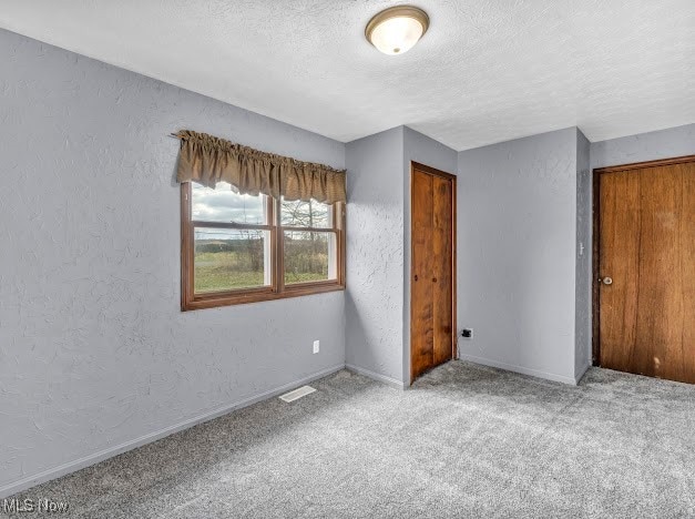 unfurnished bedroom featuring a closet, carpet, and a textured ceiling