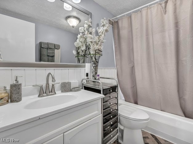 full bathroom featuring vanity, toilet, a textured ceiling, and shower / tub combo