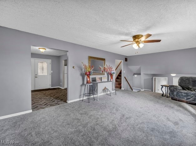 unfurnished living room with ceiling fan, dark carpet, and a textured ceiling