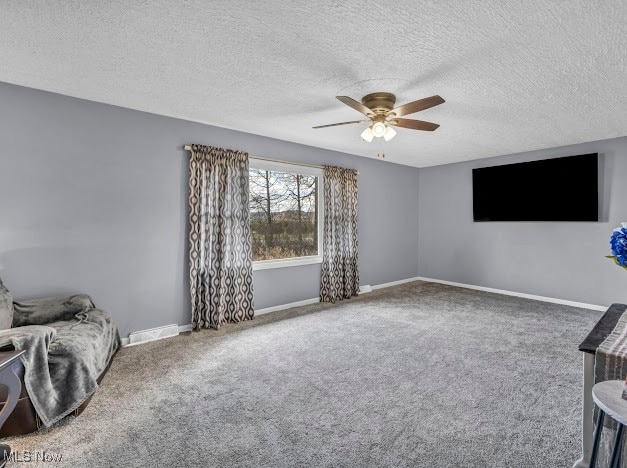 living area featuring carpet flooring, ceiling fan, and a textured ceiling