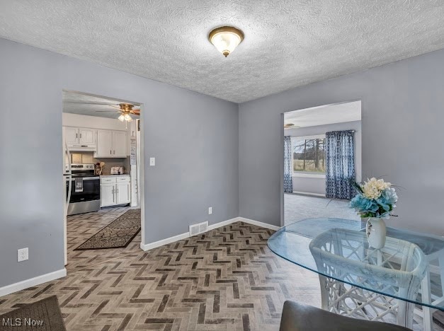 dining area featuring ceiling fan, light parquet flooring, and a textured ceiling