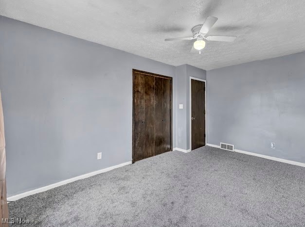 unfurnished bedroom with carpet flooring, ceiling fan, a closet, and a textured ceiling