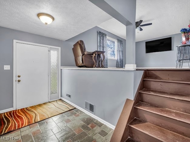 foyer entrance featuring a textured ceiling and ceiling fan