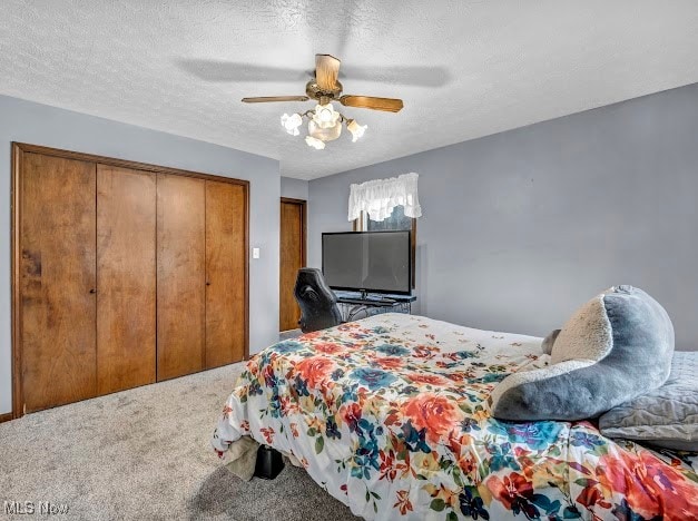 bedroom with ceiling fan, a closet, carpet floors, and a textured ceiling