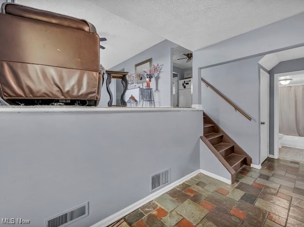 stairway with ceiling fan and a textured ceiling