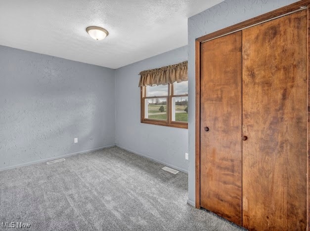 unfurnished bedroom with carpet flooring, a textured ceiling, and a closet