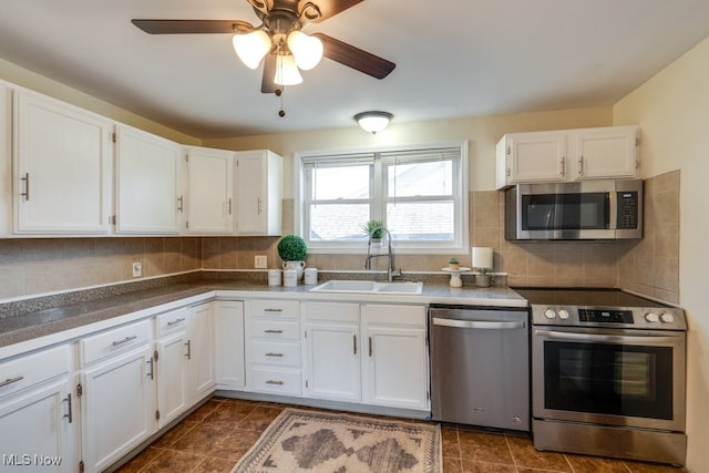 kitchen featuring appliances with stainless steel finishes, white cabinetry, sink, backsplash, and ceiling fan