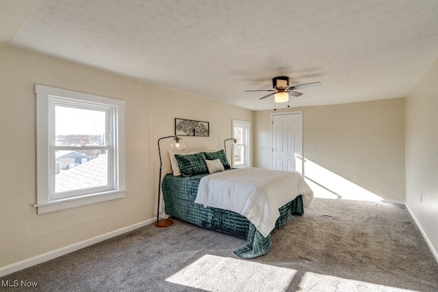 carpeted bedroom with ceiling fan, multiple windows, and a textured ceiling