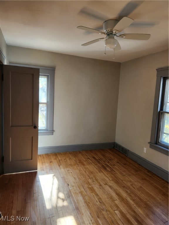empty room with ceiling fan and light hardwood / wood-style flooring
