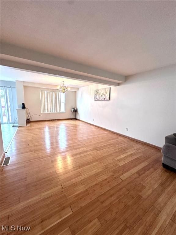 unfurnished living room featuring wood-type flooring, a wealth of natural light, and a chandelier