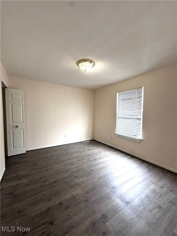 unfurnished room featuring dark wood-type flooring