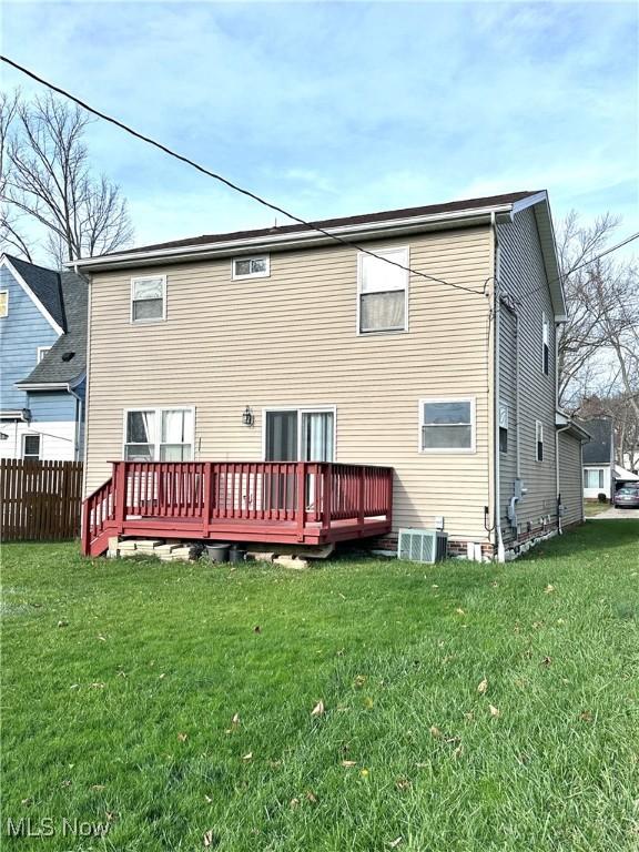 rear view of property featuring cooling unit, a yard, and a wooden deck