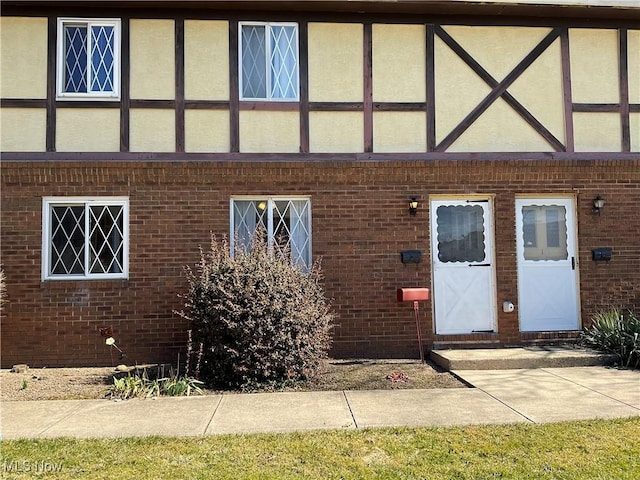 view of exterior entry featuring brick siding and stucco siding