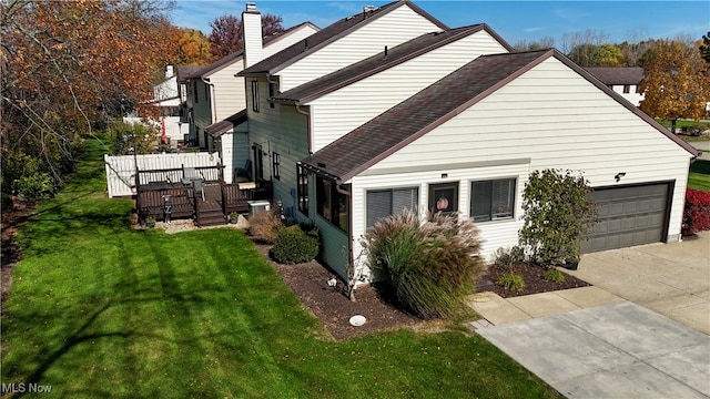 view of side of property with a garage, a yard, and a deck