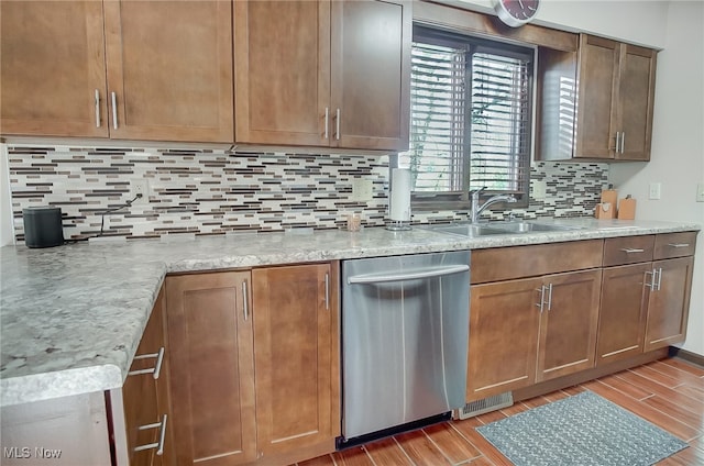 kitchen featuring dishwasher, backsplash, sink, light stone countertops, and light wood-type flooring