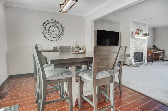 dining area featuring a fireplace, hardwood / wood-style floors, and crown molding