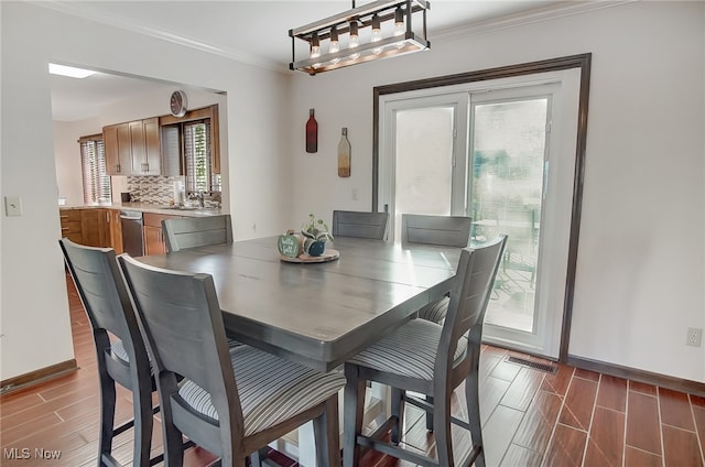 dining area with a wealth of natural light, dark hardwood / wood-style floors, and ornamental molding