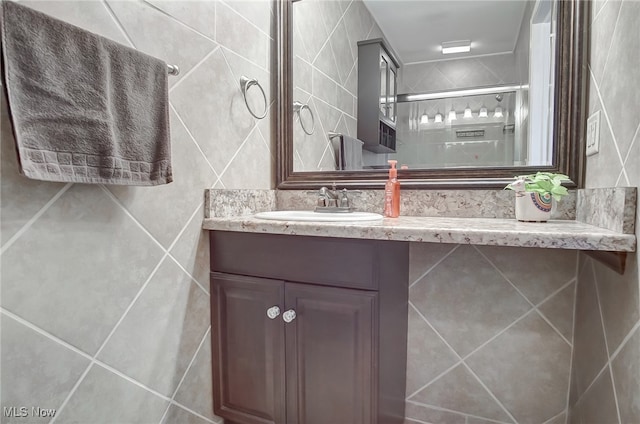 bathroom featuring vanity, a shower with shower door, and tile walls