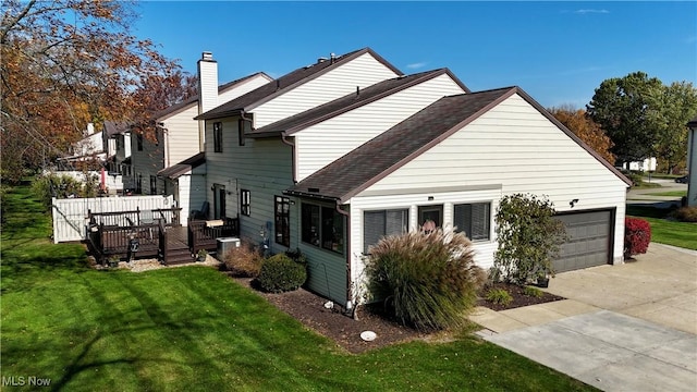 rear view of house with a yard, a garage, and a deck