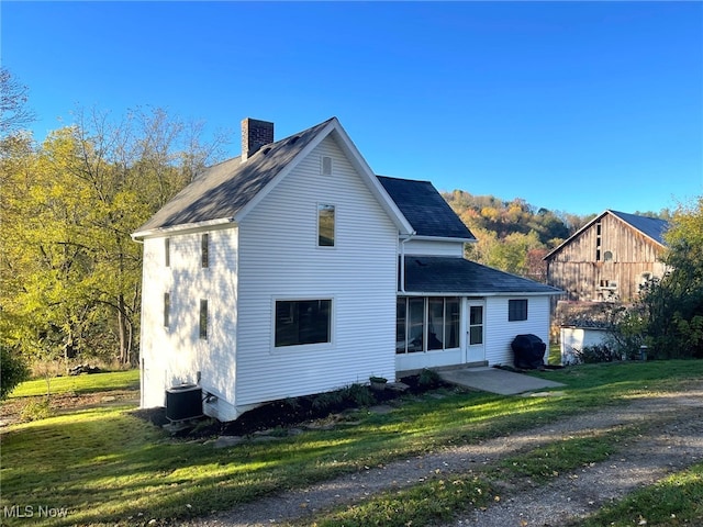 rear view of property featuring a lawn and central air condition unit