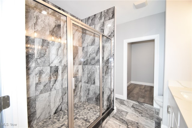 bathroom featuring vanity, toilet, and a shower with shower door