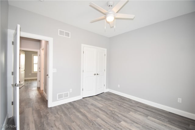 unfurnished bedroom featuring ceiling fan, a closet, and wood-type flooring