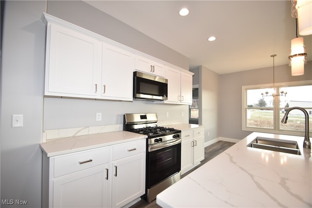 kitchen featuring sink, white cabinets, hanging light fixtures, and appliances with stainless steel finishes