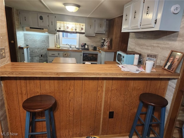 kitchen featuring kitchen peninsula, backsplash, a breakfast bar area, and sink