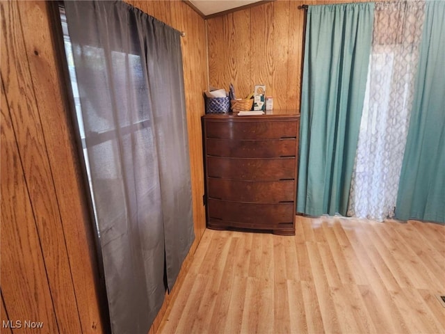 bedroom with wood walls and light hardwood / wood-style flooring